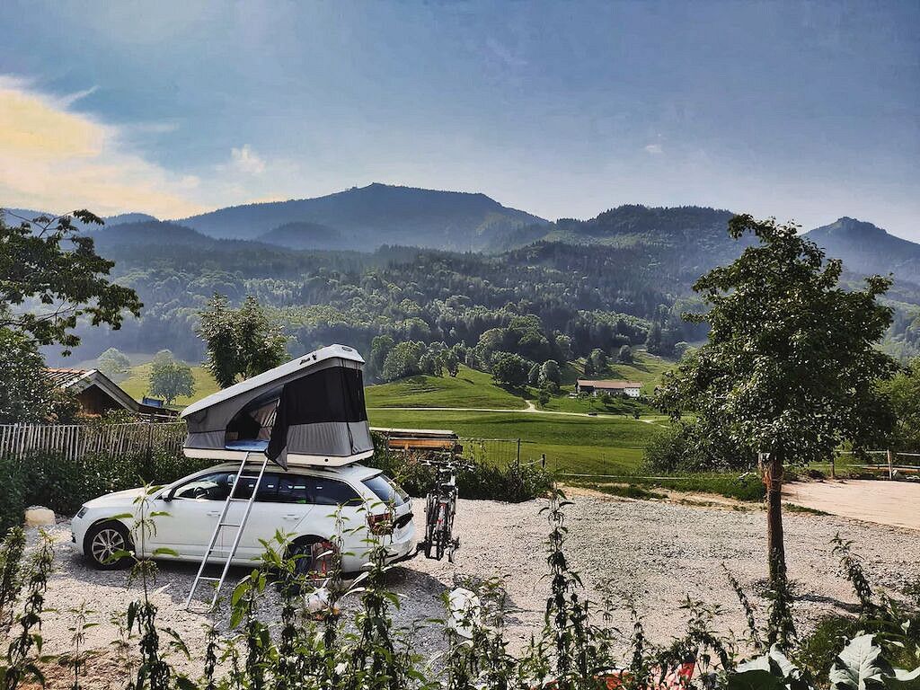 Auto mit Dachzelt auf Stellplatz vor Bergpanorama