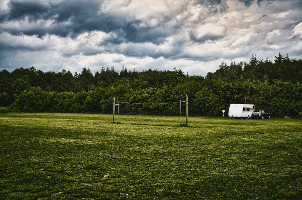 camping Stellplatz mit Wohnwagen auf grüner Wiese am Waldrand